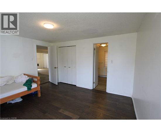 A bedroom with a bed and a wooden floor.