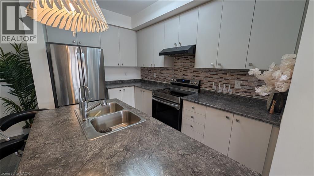 A kitchen with a granite countertop and a stainless steel refrigerator.