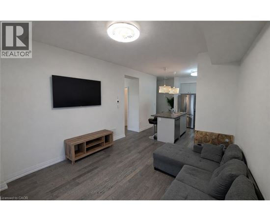 A living room with a grey couch and a flat screen TV mounted on the wall.