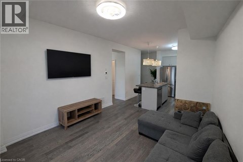 A living room with a grey couch and a flat screen TV mounted on the wall.