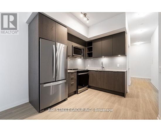 A modern kitchen with dark wood cabinets and stainless steel appliances.