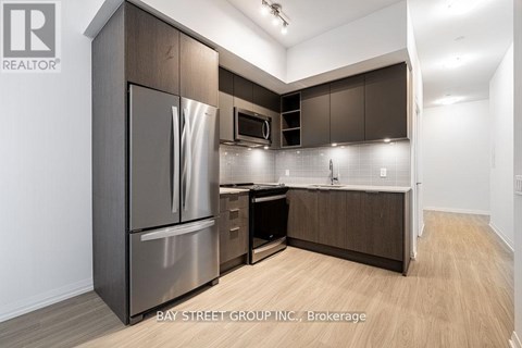 A modern kitchen with dark wood cabinets and stainless steel appliances.