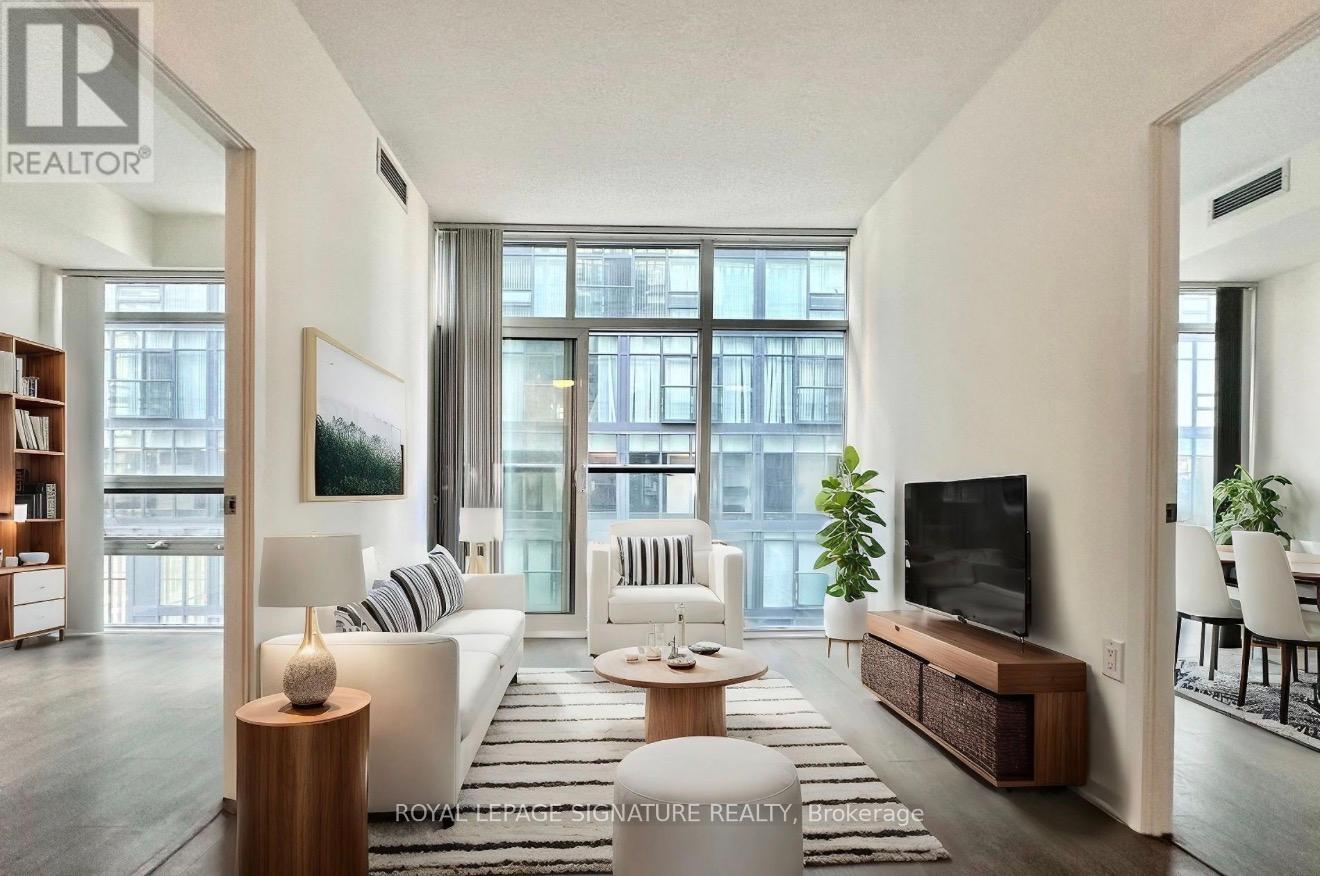 A living room with a white couch, a wooden coffee table, and a large window.