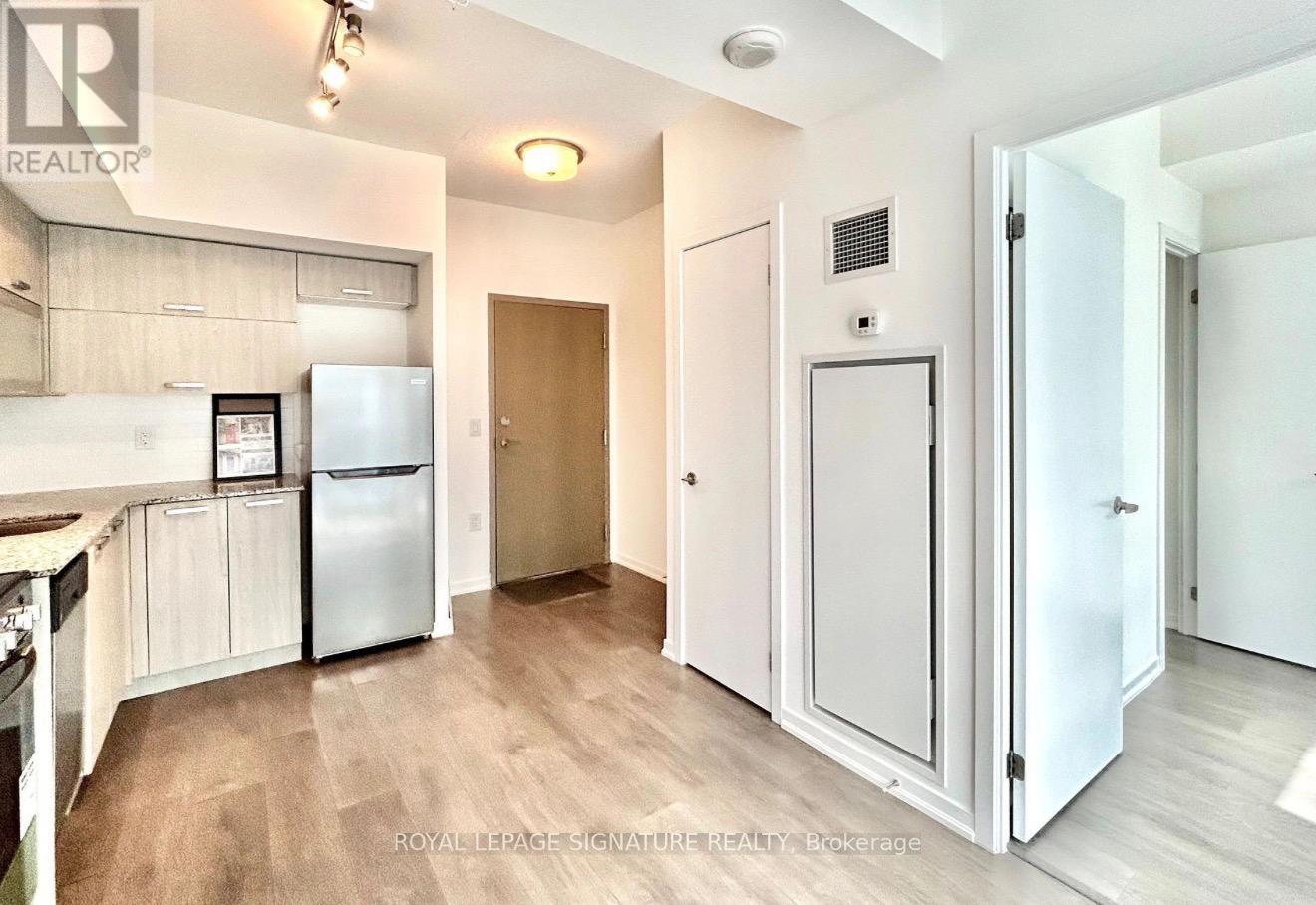 A kitchen with a refrigerator, cabinets, and a countertop.