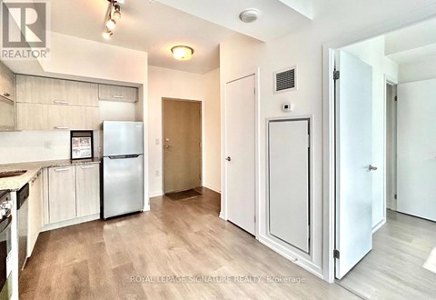 A kitchen with a refrigerator, cabinets, and a countertop.