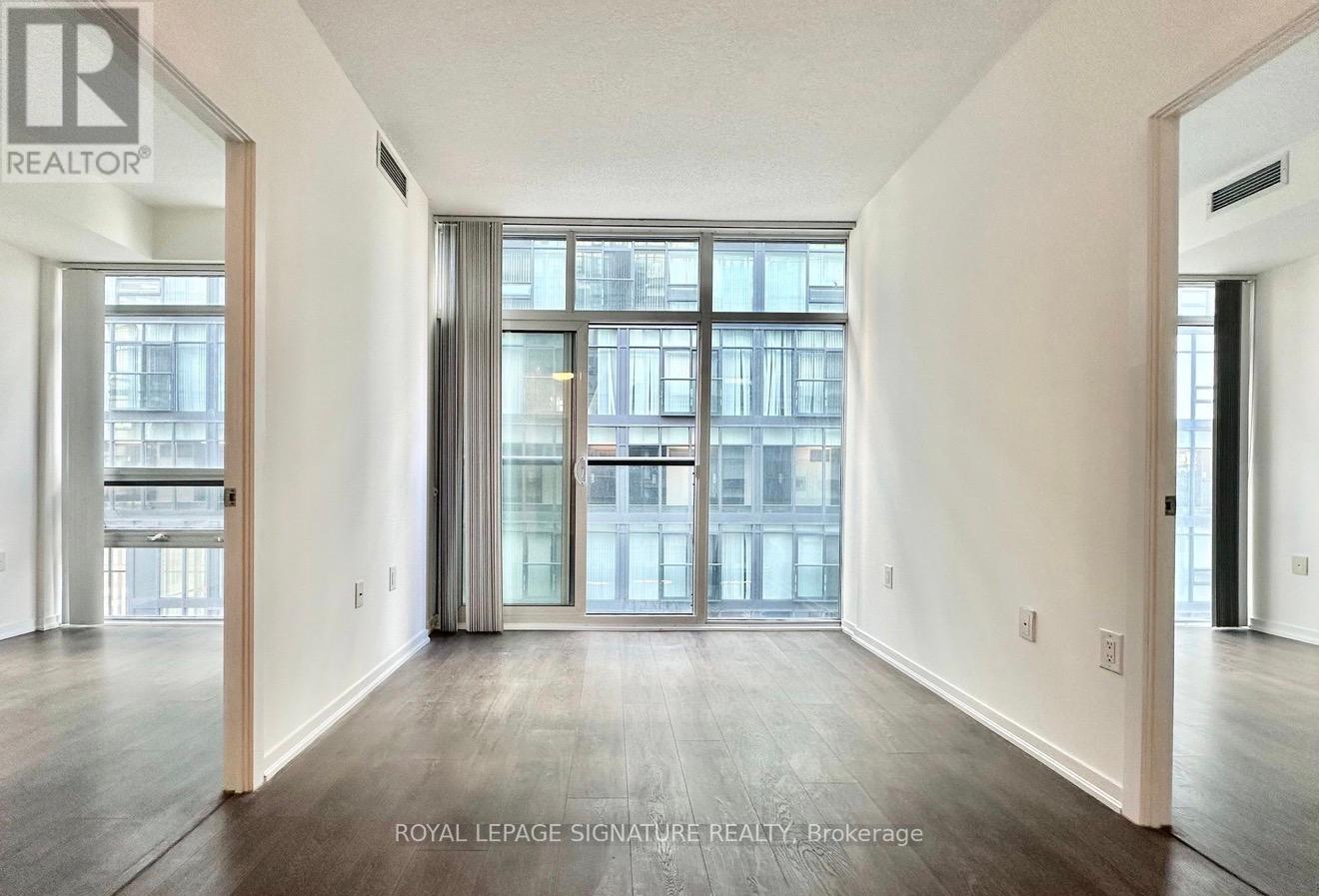 A spacious room with wooden floors and a large window with a view of a cityscape.