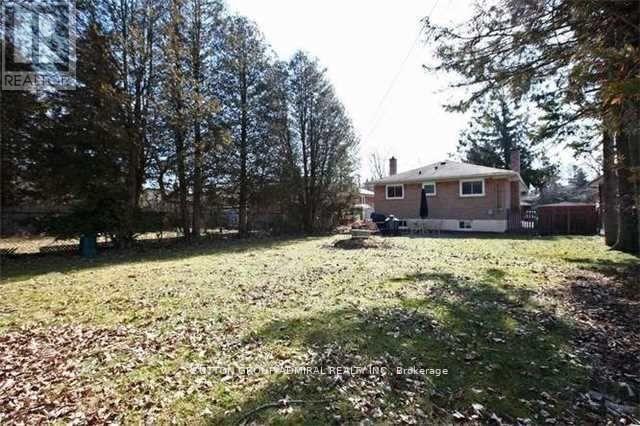 A house with a brown roof and a white fence is surrounded by trees.