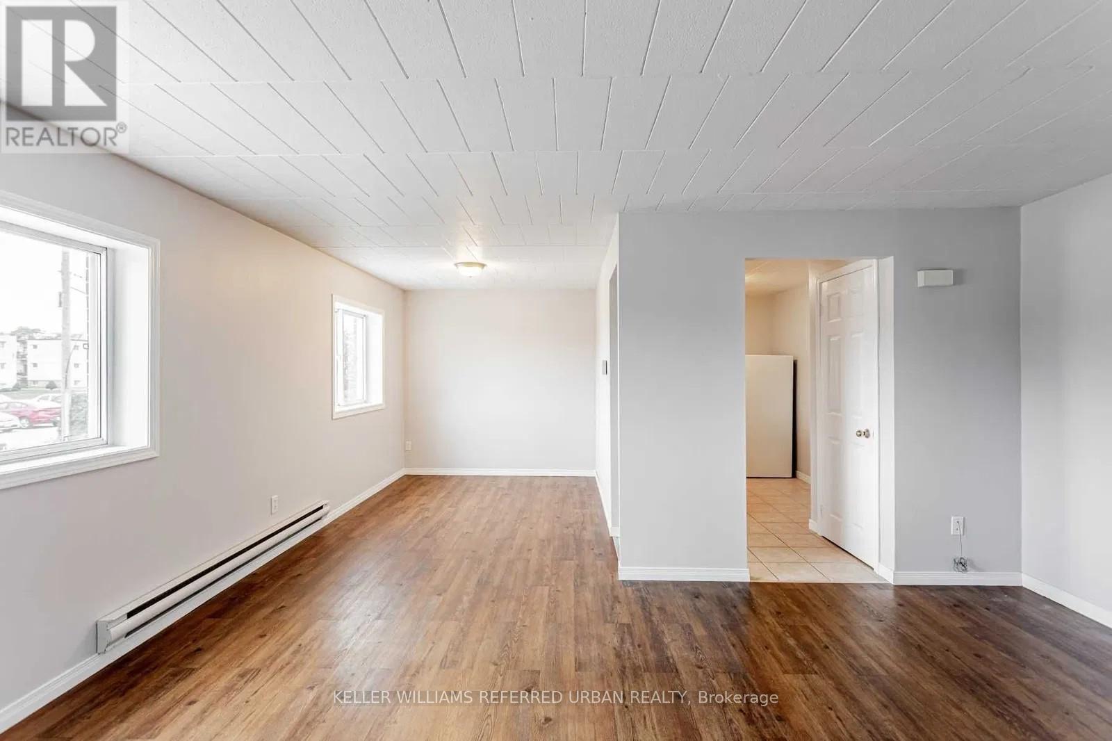 A spacious room with wooden floors and white walls.