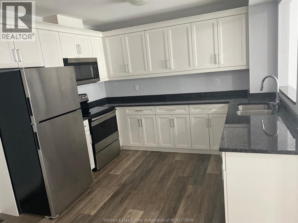 A kitchen with white cabinets and a black fridge.