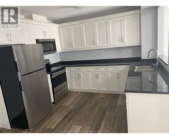 A kitchen with white cabinets and a black fridge.