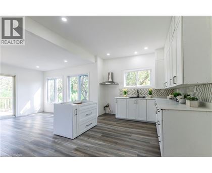 A modern kitchen with white cabinets and a wooden floor.
