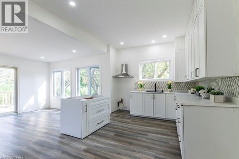 A modern kitchen with white cabinets and a wooden floor.