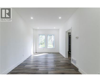 A spacious room with wooden flooring and a large window.