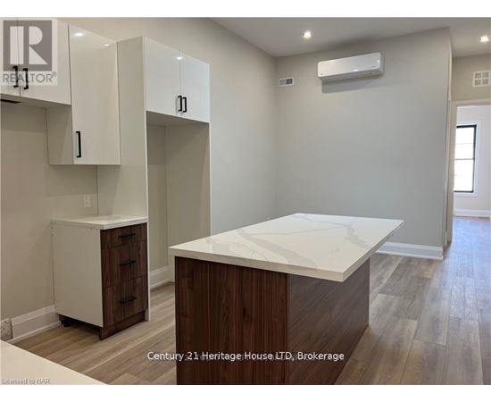 A kitchen area with a white countertop and wooden cabinets.