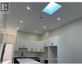A modern kitchen with white cabinets and a skylight.