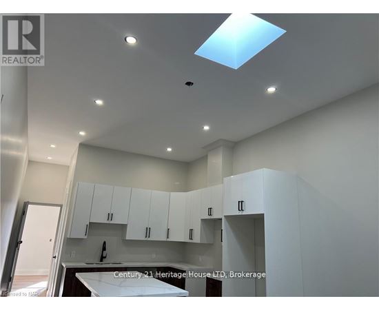 A modern kitchen with white cabinets and a skylight.