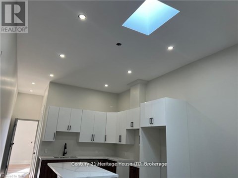 A modern kitchen with white cabinets and a skylight.