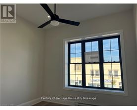 A room with a ceiling fan and a window showing a building outside.