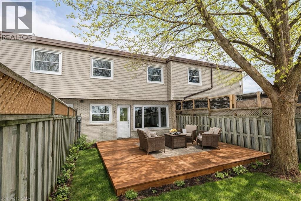 A wooden deck with a table and chairs is in front of a house.