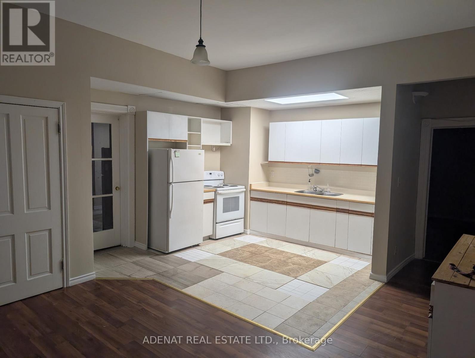 A kitchen with white appliances and wooden floors.