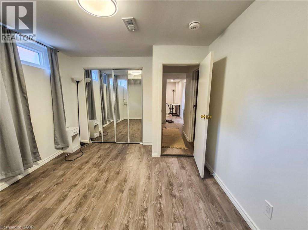 A spacious room with wooden flooring and a large mirror on the wall.