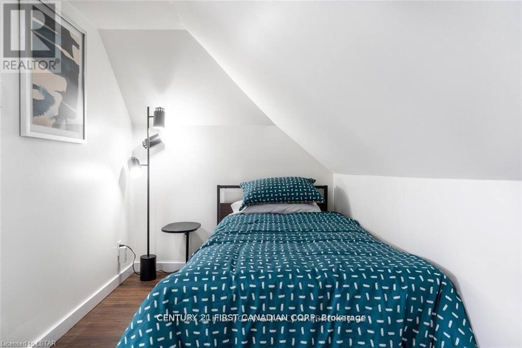 A bedroom with a bed, a small table, and a lamp.