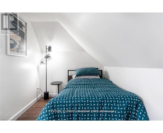 A bedroom with a bed, a small table, and a lamp.