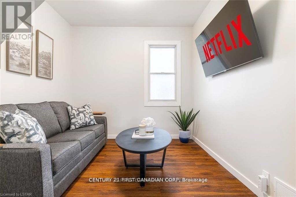 A living room with a grey couch, a black coffee table, a plant, and a Netflix sign on the wall.