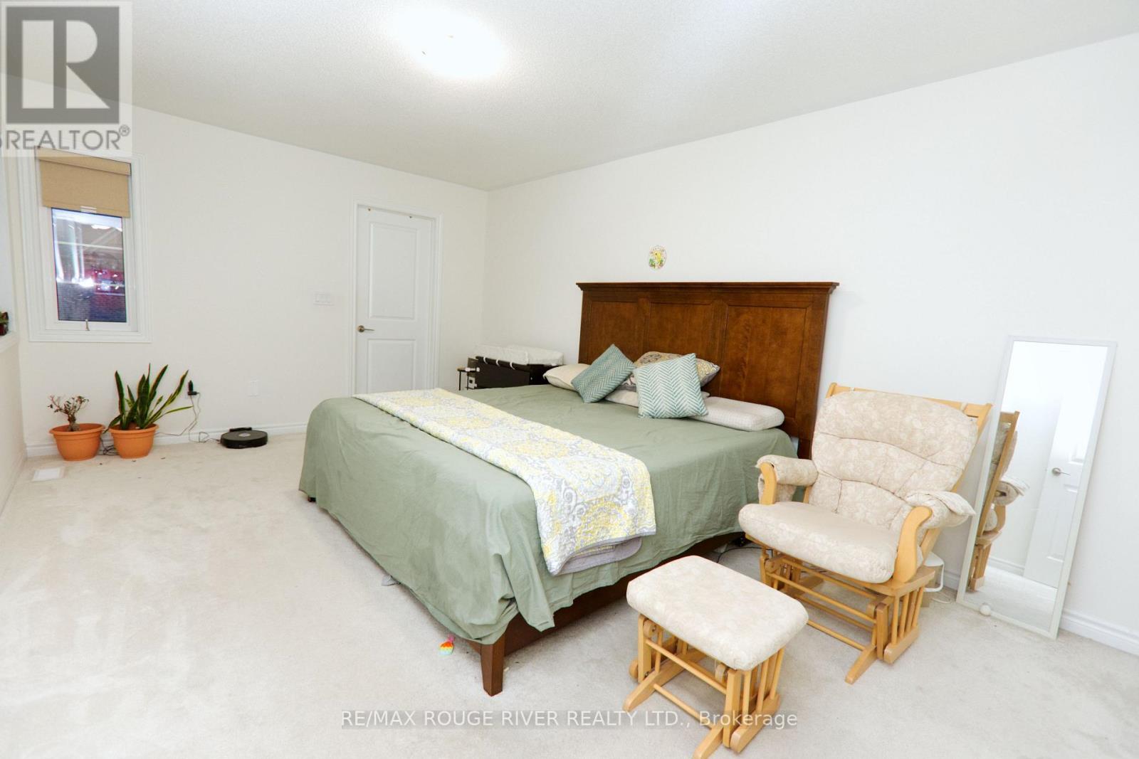 A bedroom with a bed, chair, and potted plants.