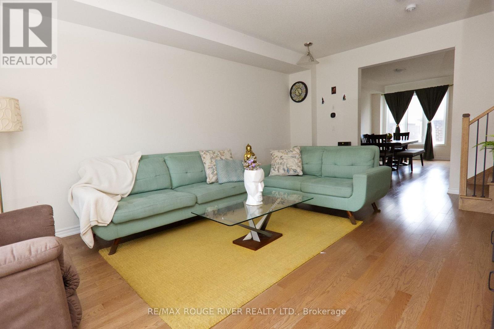 A living room with a green couch and a glass coffee table.