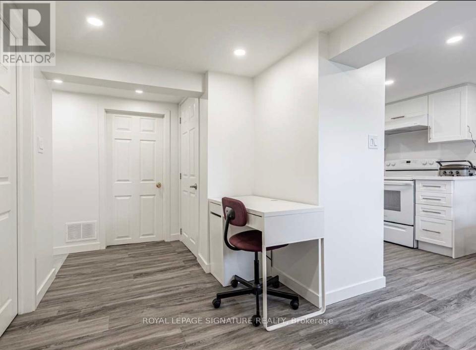 A white kitchen with a desk and chair in the middle.