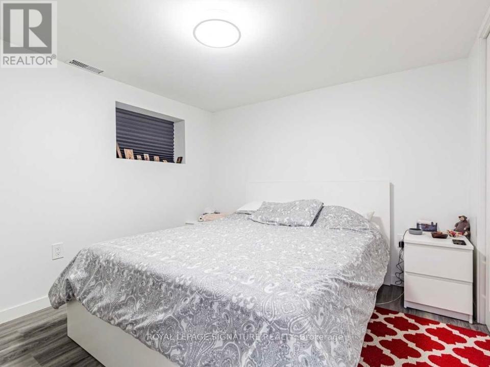 A bedroom with a bed, nightstand, and window.