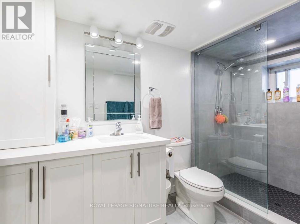 A white bathroom with a toilet, sink, and shower.
