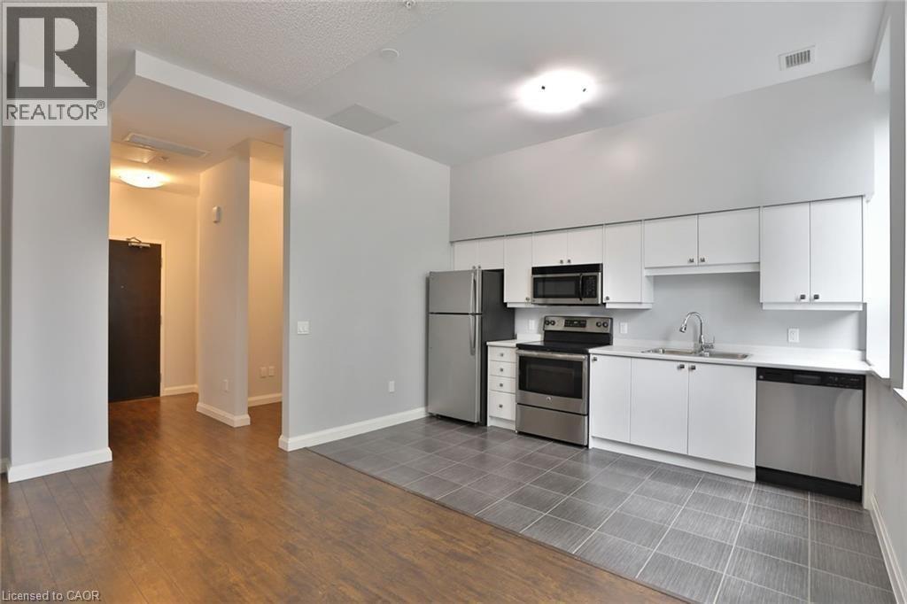 A kitchen with white cabinets and a black fridge.