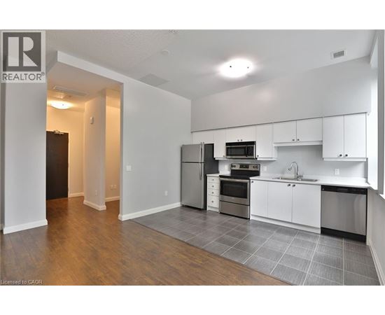 A kitchen with white cabinets and a black fridge.