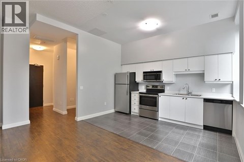 A kitchen with white cabinets and a black fridge.