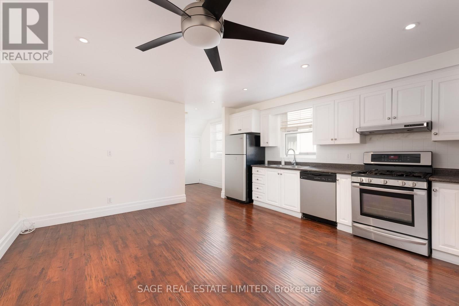 A well-lit kitchen with a wood floor and white cabinets.