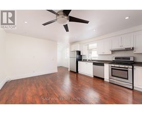 A well-lit kitchen with a wood floor and white cabinets.