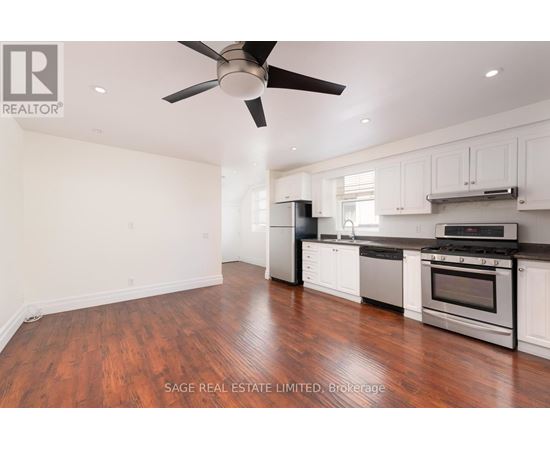 A well-lit kitchen with a wood floor and white cabinets.