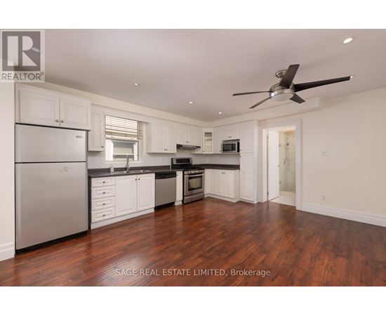 A well-lit kitchen with white cabinets and a wooden floor.