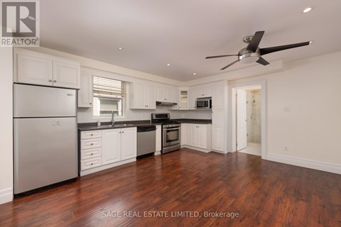 A well-lit kitchen with white cabinets and a wooden floor.