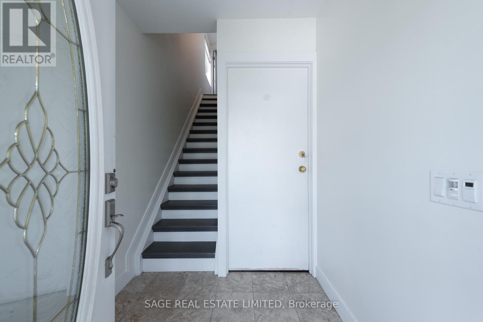 A hallway with a staircase and a white door.
