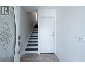 A hallway with a staircase and a white door.