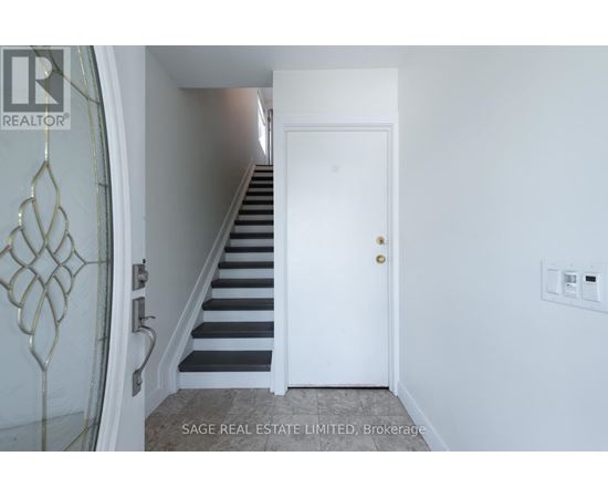 A hallway with a staircase and a white door.