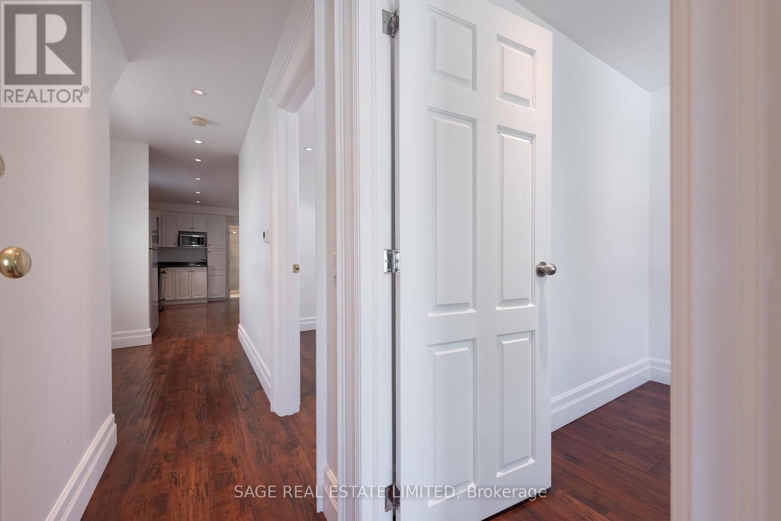 A hallway with a white door and a wooden floor.