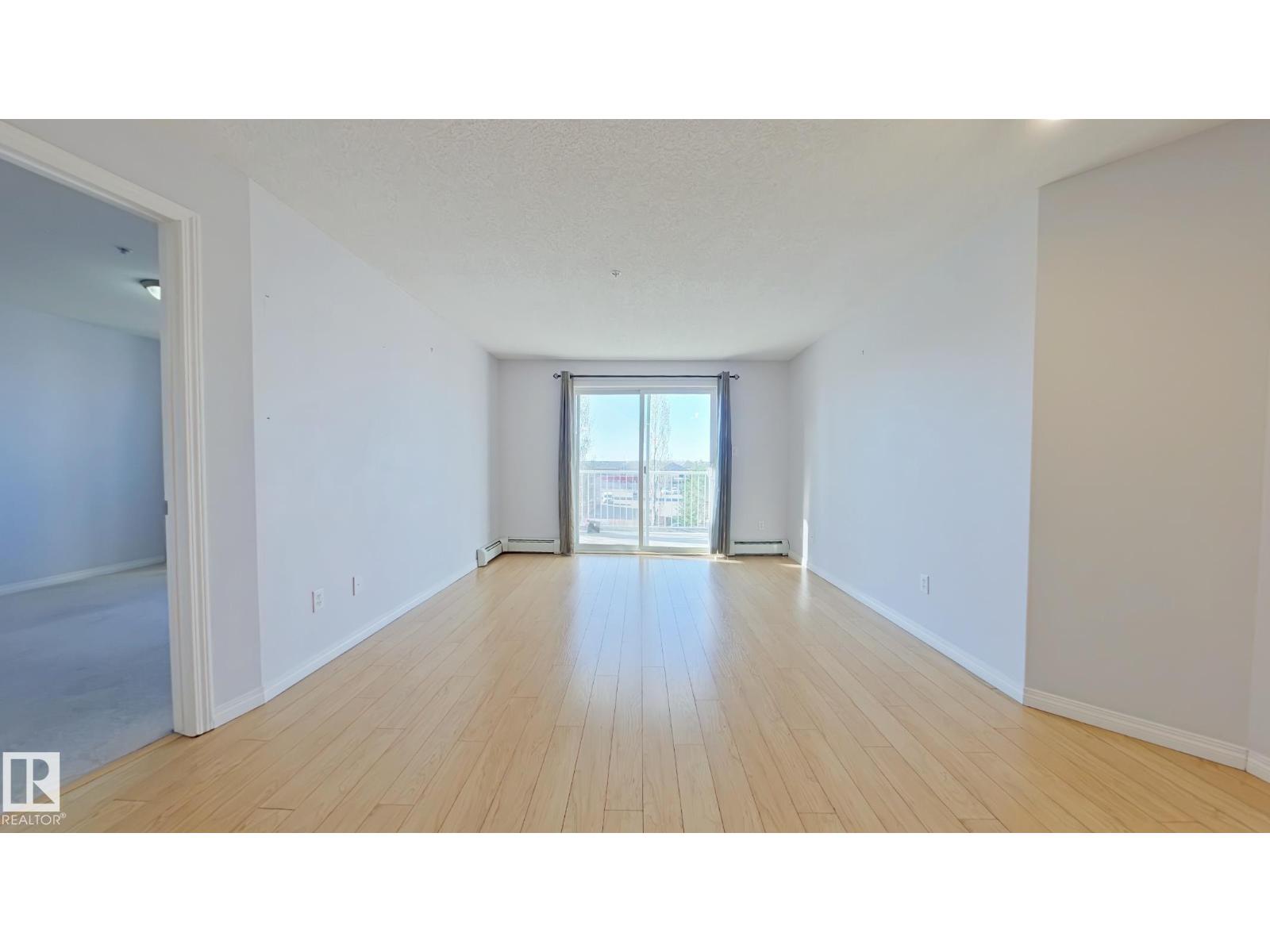 A spacious room with wooden floors and white walls.