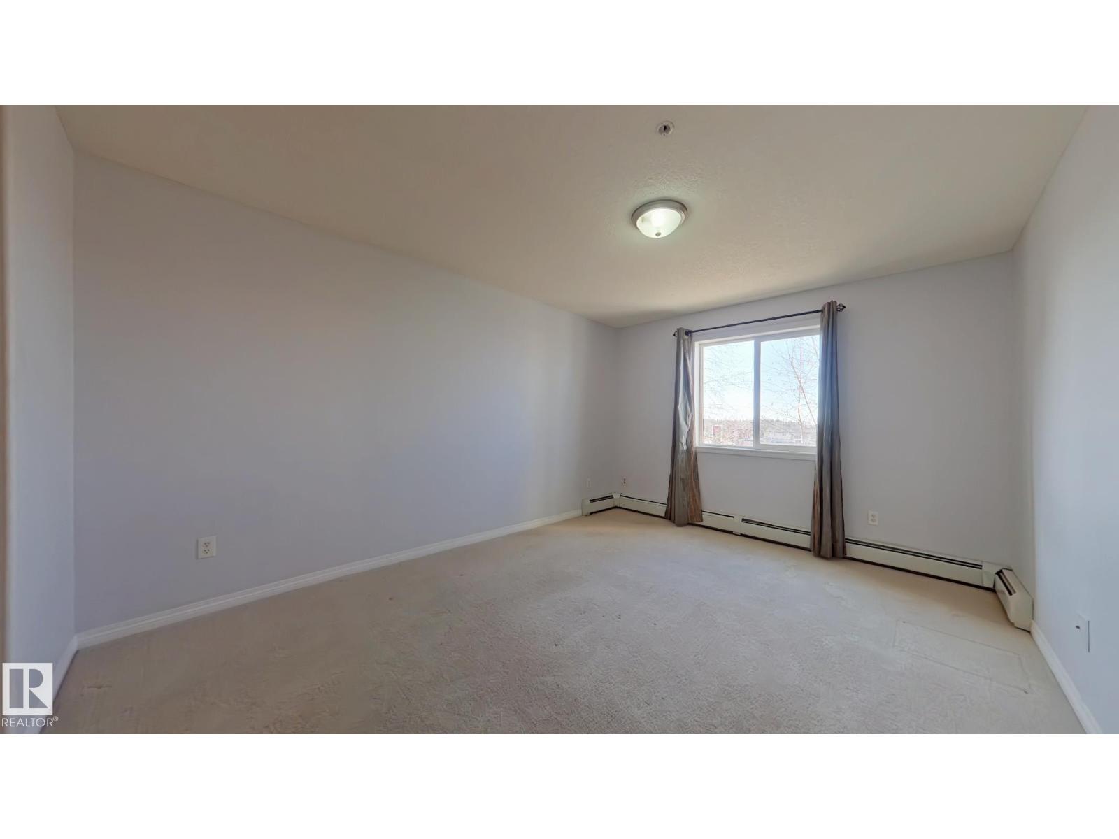 A spacious room with a window and a carpeted floor.
