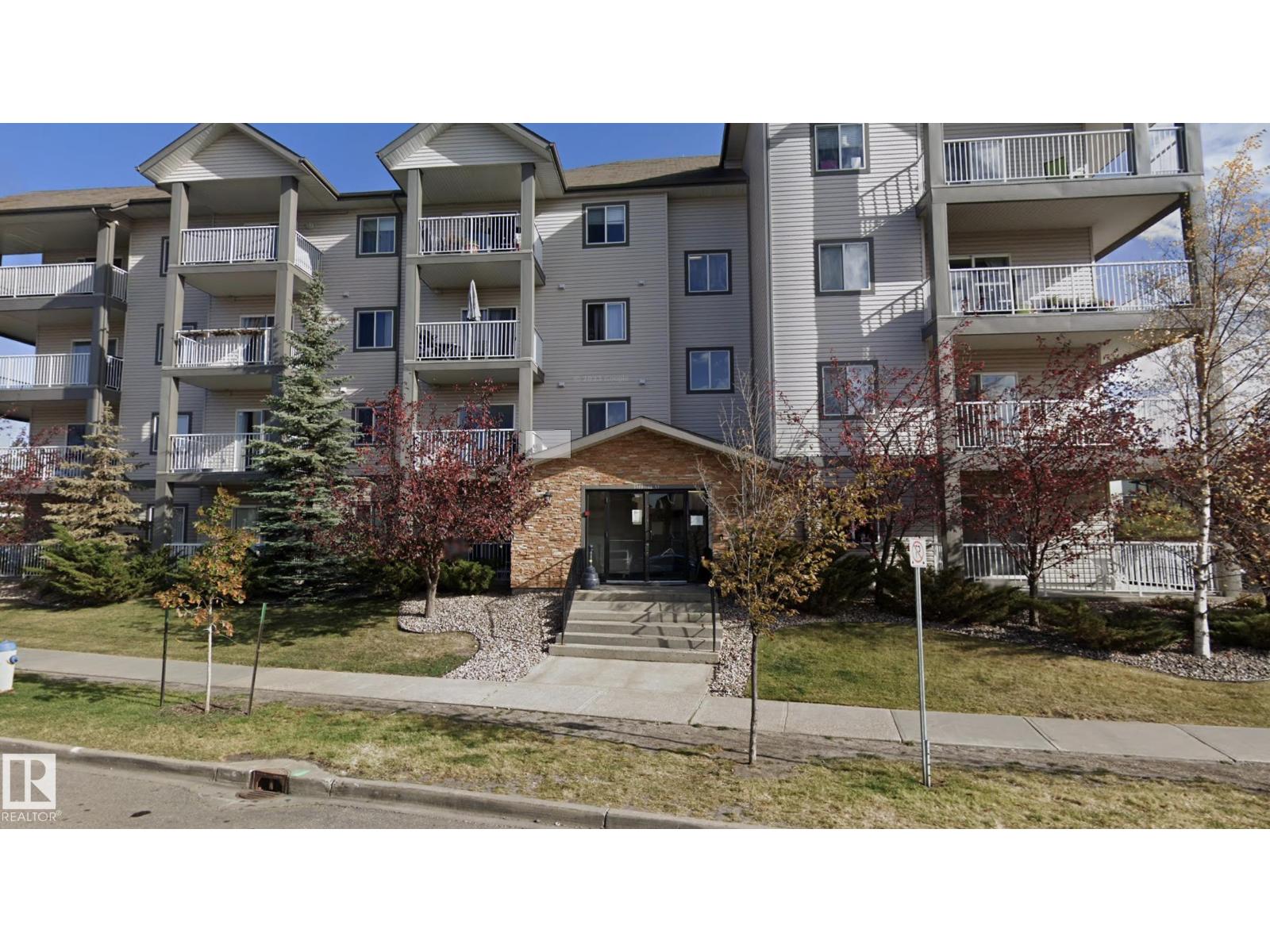 Apartment building with a front entrance and a small garden area.
