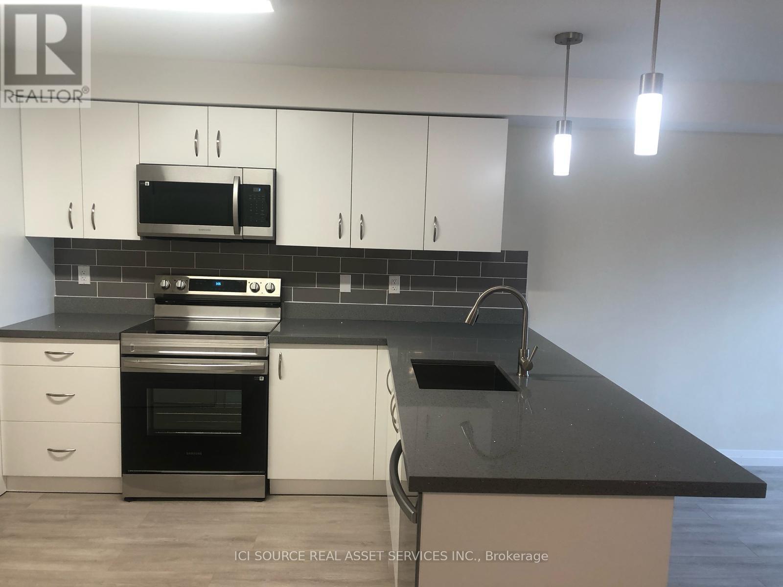 A modern kitchen with white cabinets and black countertops.