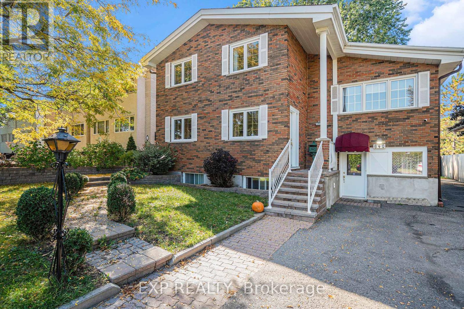 A house with a brick facade and a red awning is for sale.